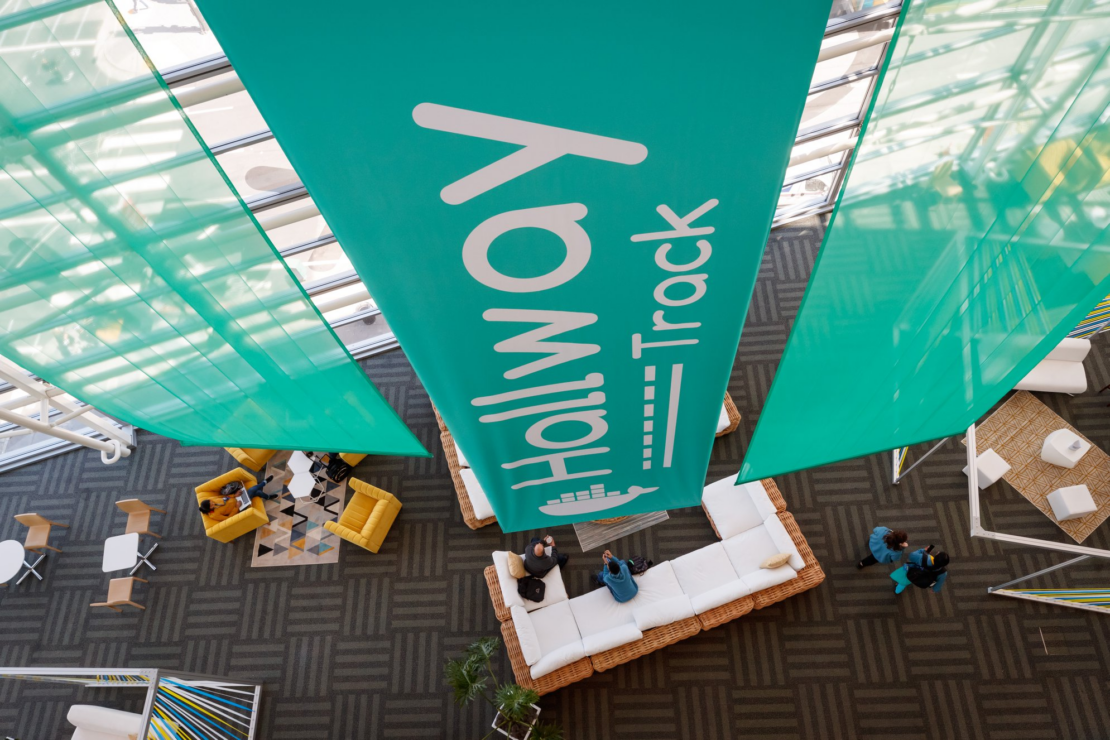 Photo of large green "Hallway track" banner hanging in front of a wall of windows.